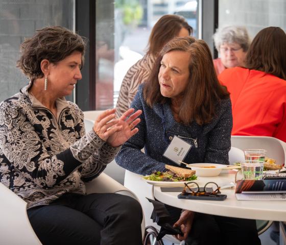 Two women converse at a table.