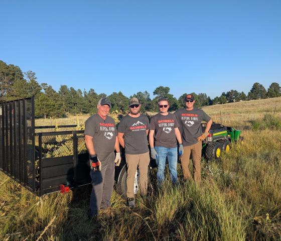 Volunteers stand in front of a trail filled with invasive weeds.