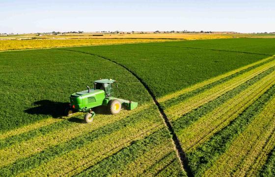 Aerial photo of a verdant farm with a green tractor in the field