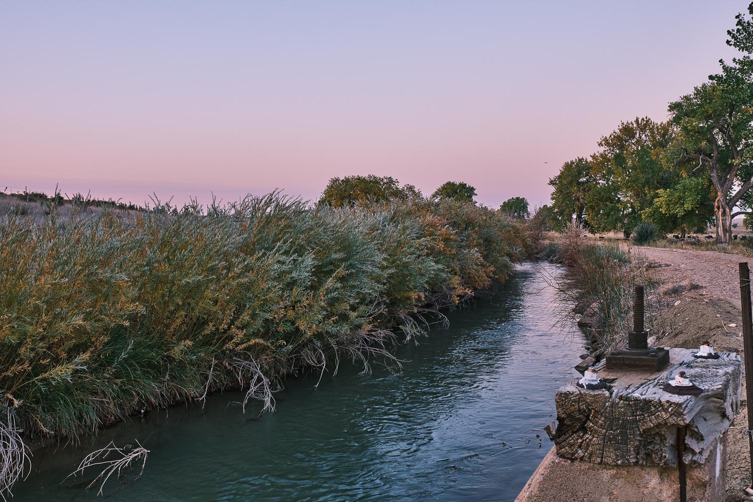 pink dusk sky over irrigation ditch.