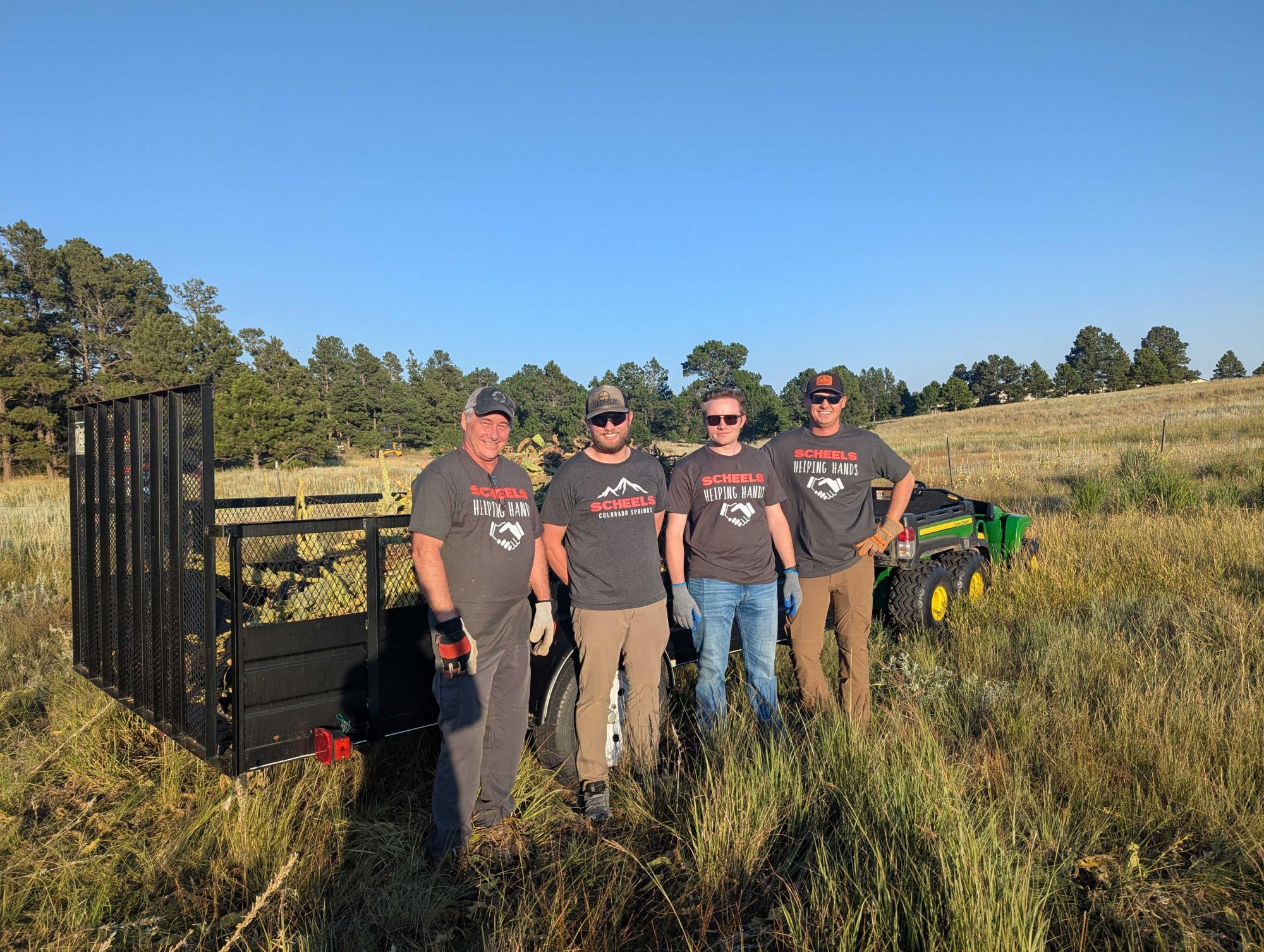 Volunteers stand in front of a trail filled with invasive weeds.